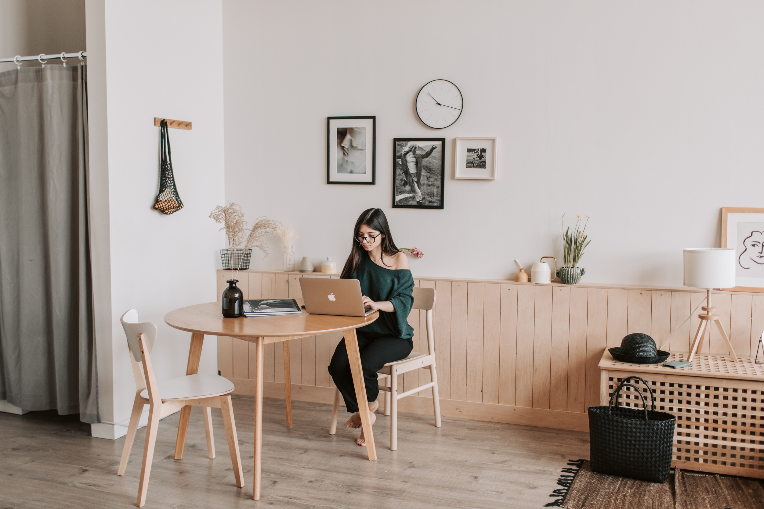 Woman working on laptop at table in modern apartment